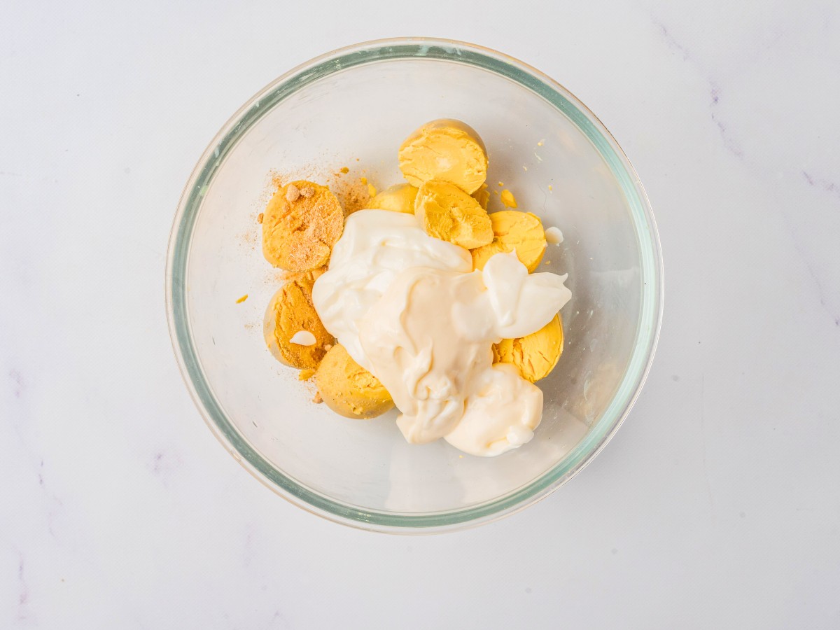 adding mayo and greek yogurt to egg yolks.